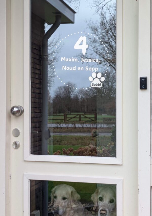 Voordeur met op het glas een opdruk van een cirkel van stippen en een dierenpoot met een naam, in het midden staat het huisnummer en de namen.