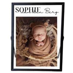 Een zwart fotolijstje met daarin een foto van een baby met een opdruk van de voornaam met daaronder de achternaam in sierlijke letters.