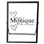 Een zwart fotolijstje met een opdruk van een naam met daarachter hartjes en onder de naam staat de tekst: ik mis je.