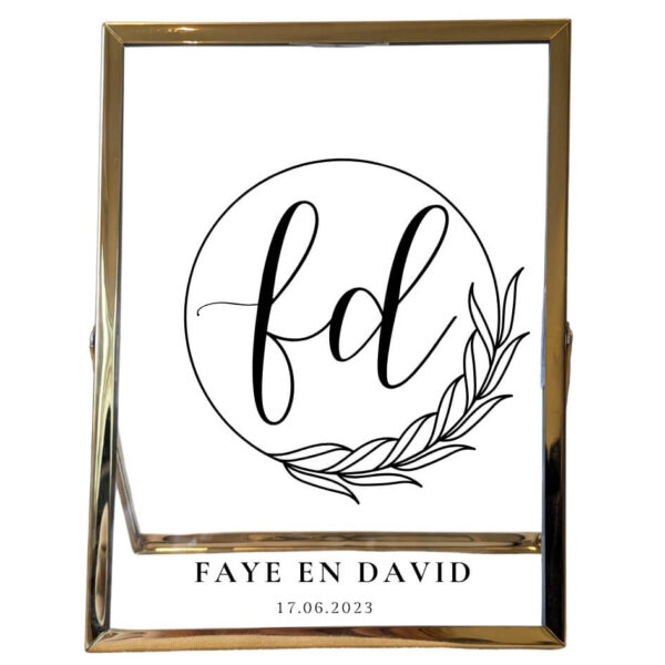 Een gouden fotolijst met daarin een sierlijke cirkel met blaadjes. In de cirkel staan 2 initialen en onder de cirkel staan 2 namen met de datum.