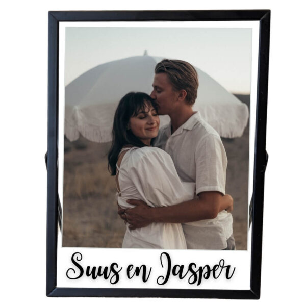 Een zwarte fotolijst met daarin een foto van een verliefd stel met daaronder een opdruk van twee namen.