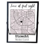 Een zwart fotolijstje met een stadsplattegrond met daarboven de tekst: love at first sight en daaronder een opdruk van de plaatsnaam en land.