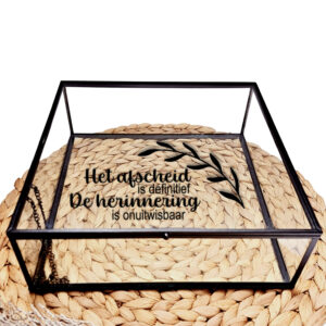 Glazen kistje met zwart frame en bedrukking van een olijftak met de tekst: Het afscheid is definitief, de herinnering is onuitwisbaar.