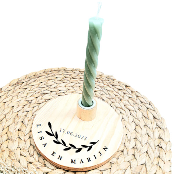 Ronde blanco houten kaarsenstandaard met een zwarte opdruk van in cirkelvormig geschreven namen met daarboven een olijftak en de datum