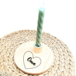 Ronde blanco houten kaarsenstandaard met een zwarte opdruk van een hartje met daarin een naam in sierlijke letters.