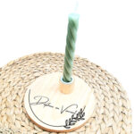 Ronde blanco houten kaarsenstandaard met een zwarte opdruk van gebogen tak met daarboven de namen in sierlijk lettertype