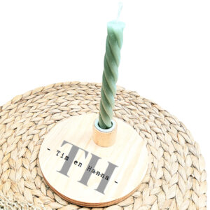 Ronde blanco houten kaarsenstandaard met een opdruk van grijze initialen met daarop in het zwart de namen uitgeschreven.