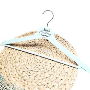 Een wit houten kleerhanger met daarop de bedrukking van mrs of mr met daaronder de achternaam in sierlijke letters en de datum dik gedrukt.