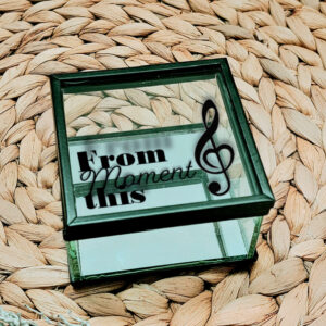 Vierkant glazen kistje met zwart frame en een opdruk van een muzieksleutel met tekst: from this moment, waarvan moment in sierlijk lettertype