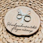 Rond ringplankje gemaakt van een boomstamschijf met ringen aan satijnen lint en een zwarte opdruk naar eigen ontwerp, tekst of handschrift