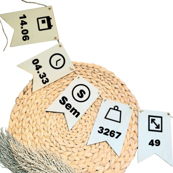 Blanco houten vlaggenlijn met op elk vlaggetje een zwarte opdruk van een geboortegegeven zoals de naam, datum, tijd, gewicht en lengte met bijpassende symbolen.