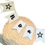 Blanco houten vlaggetjes aan een jute touw met op elke vlag een zwarte letter die samen een naam vormen en op de buitenste vlaggen een ster.